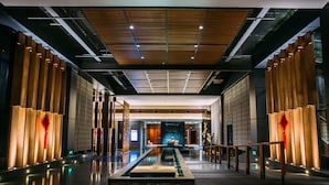 Eine geräumige Lobby mit spiegelndem Boden, einer zentralen Wasserspende und moderner Holzvertäfelung an den Wänden.