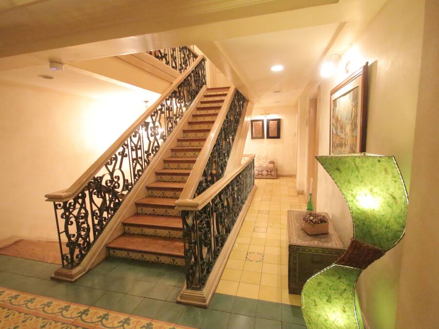 Una escalera con barandillas de metal decoradas y un suelo con diseño.