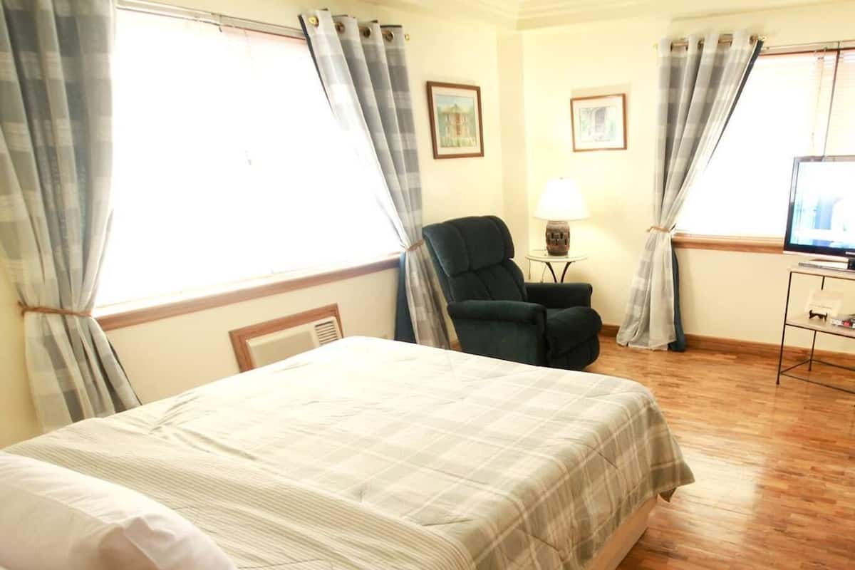 Een slaapkamer met een bed, een stoel, een lamp en een televisie.