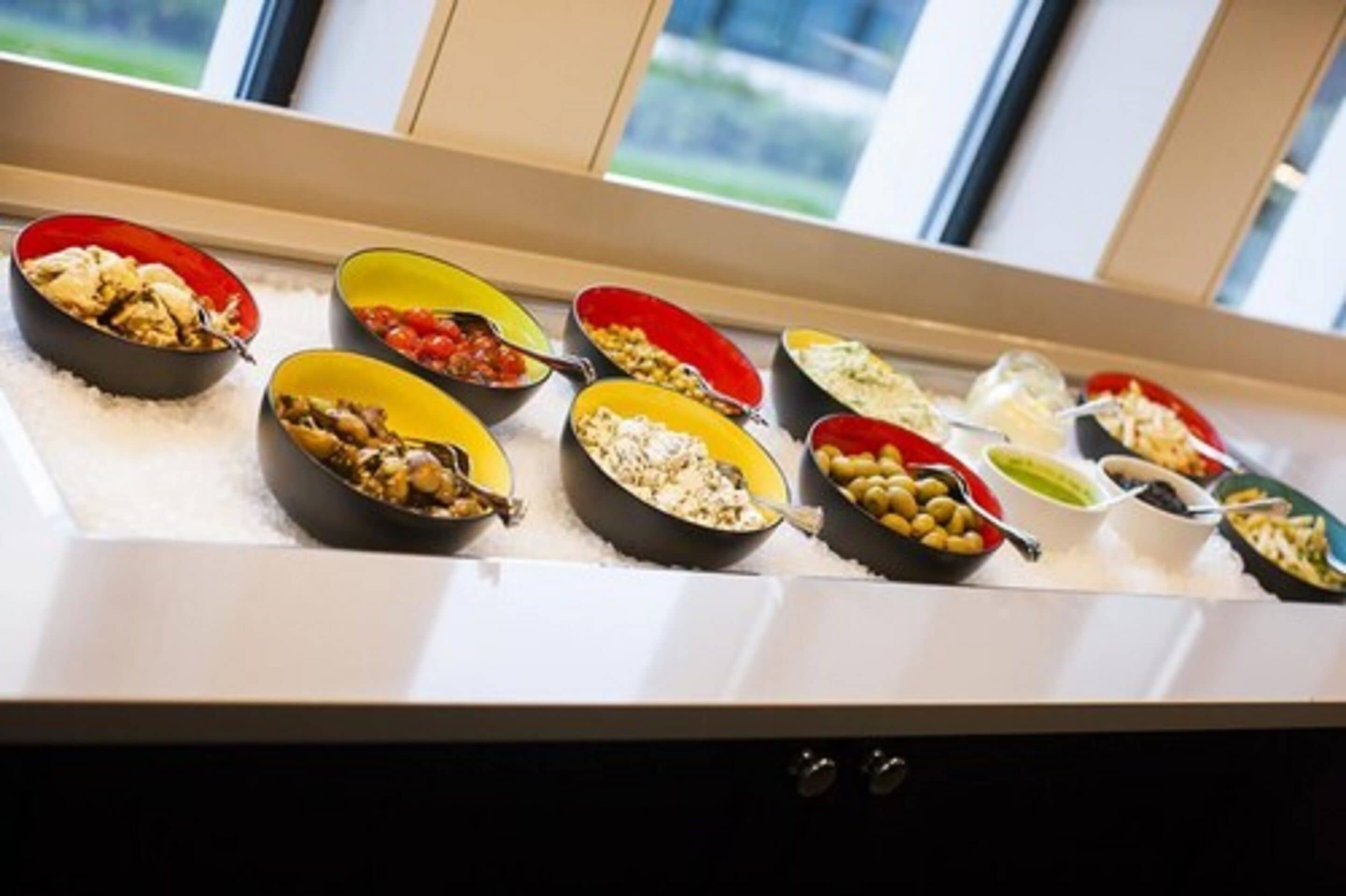 A buffet with various dishes in colorful bowls.