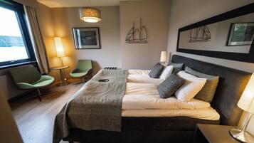 Een hotelkamer met een bed, een stoel, een lamp en kunstwerken aan de wanden.
