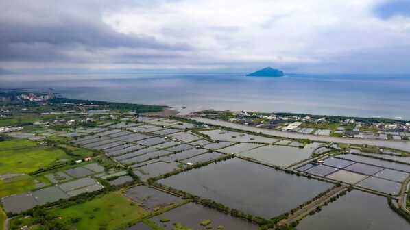 An aerial view of a coastal area with multiple water bodies and green fields. - Waterbirds Family (Toucheng)