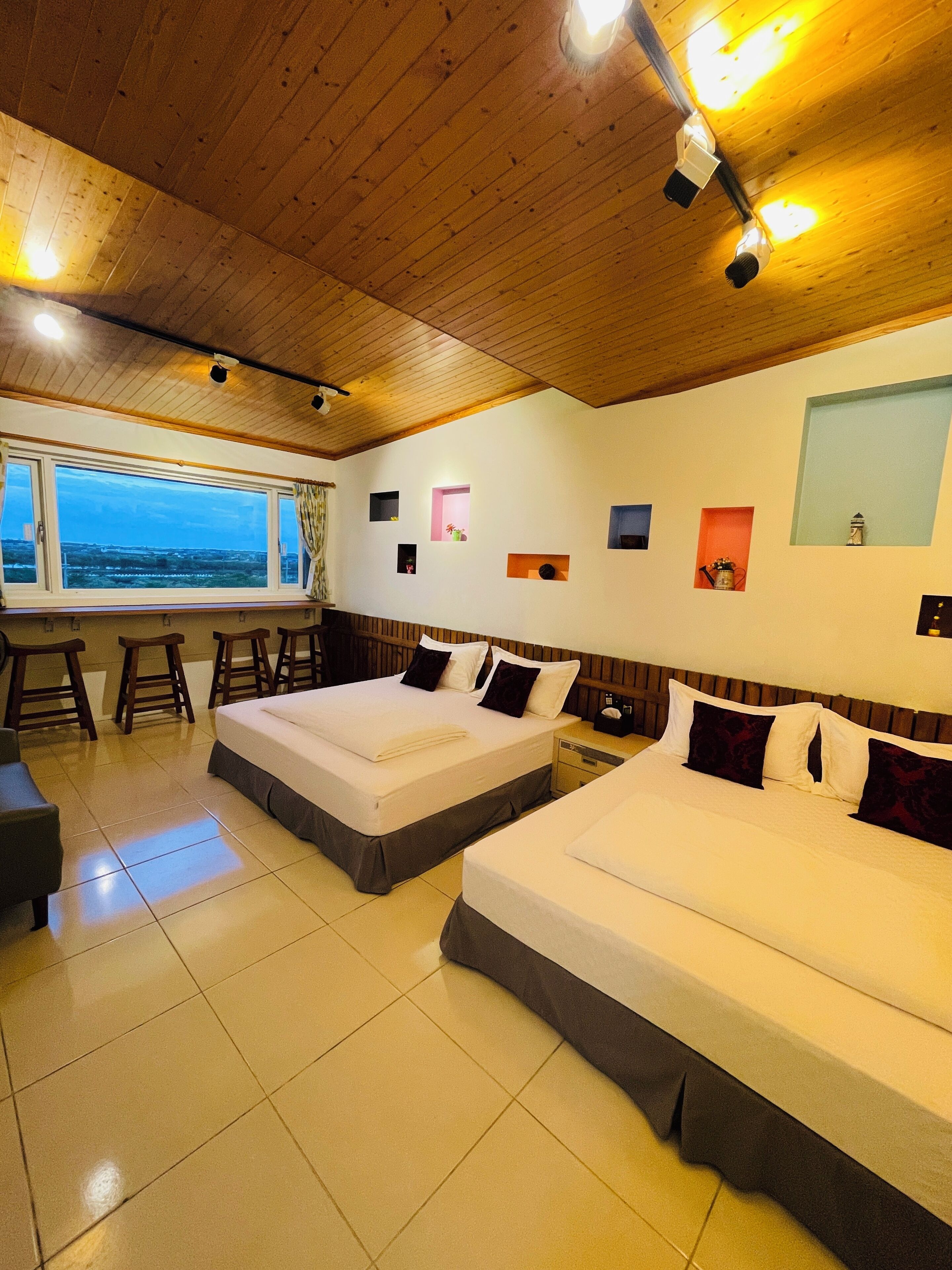 Une chambre d’hôtel avec deux lits, une fenêtre donnant sur un beau paysage et un plafond en bois.