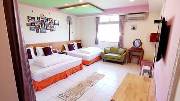 Habitación de hotel con dos camas, una mesita, una silla, un sofá, un espejo y un muro decorado con imágenes.