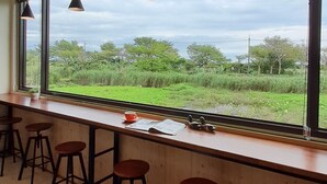 A bar area with high windows, stools, and hanging pendant lights. - Waterbirds Family (Toucheng)