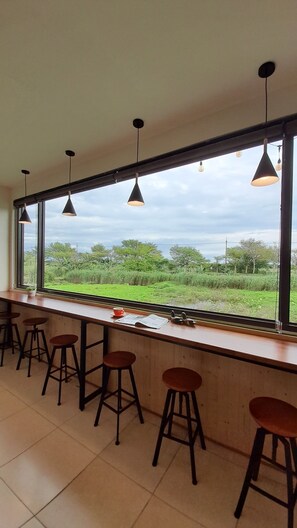 A bar area with high windows, stools, and hanging pendant lights. - Waterbirds Family (Toucheng)
