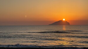 Ein Sonnenuntergang über dem Meer mit einer entfernten Insel.