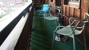 Een balkon met een groen tapijt, twee stoelen en een kleine tafel.