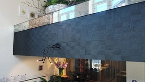 Een modern interieur met een donkere, gestructureerde muur, een receptiebalie en potplanten.