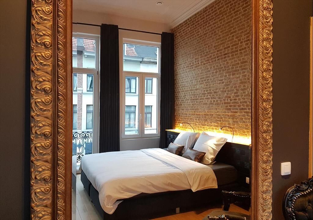 Un dormitorio con una cama grande, una pared de ladrillo y vistas a edificios.