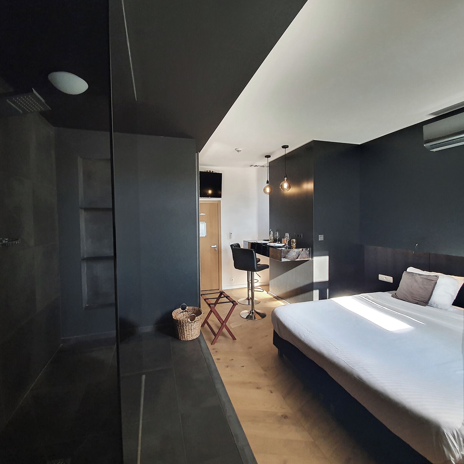 Un dormitorio moderno con una cama grande, un escritorio pequeño y una silla. Hay un armario y un espejo en la pared.