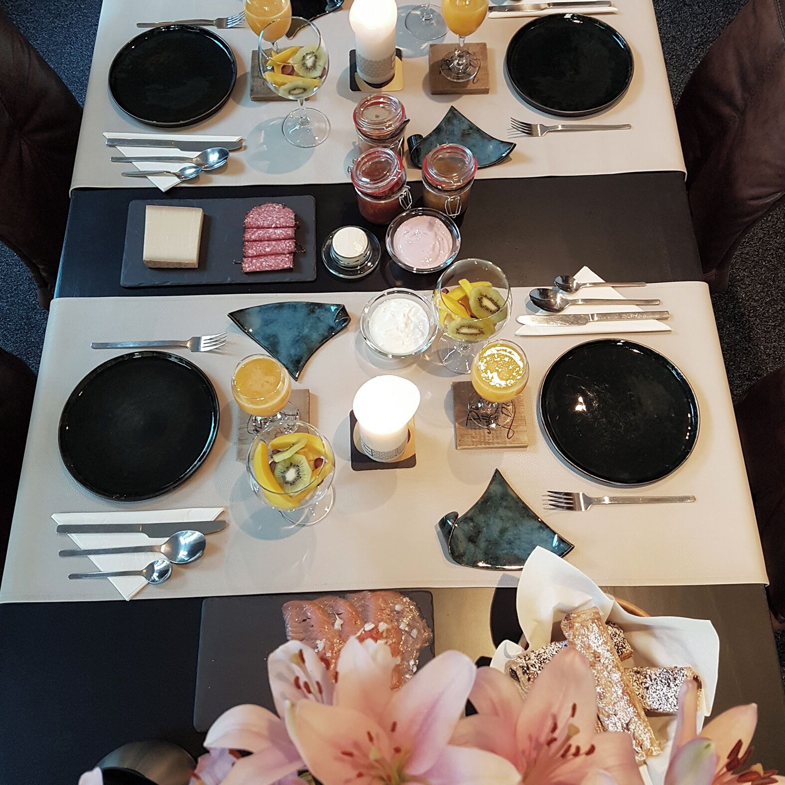 A table set for a meal with black plates, cutlery, and various condiments.