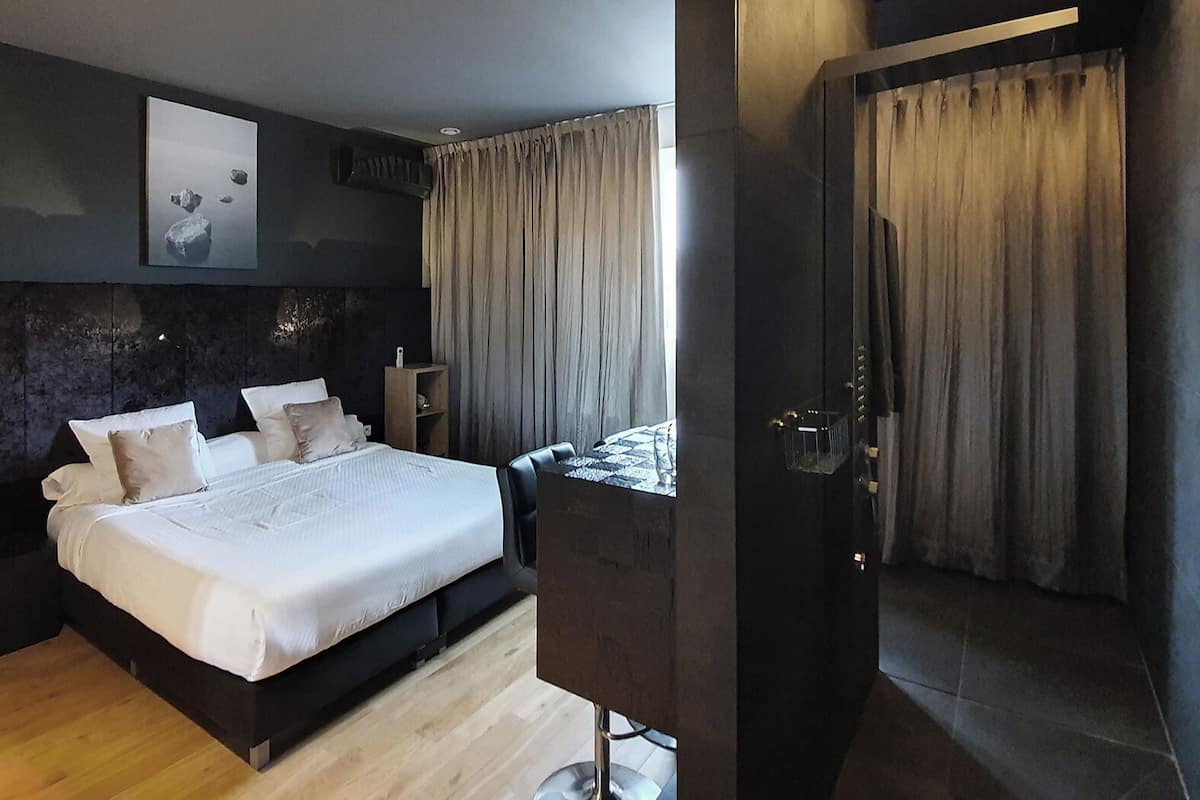A modern bedroom with a large bed, a bedside table, and a mirror.