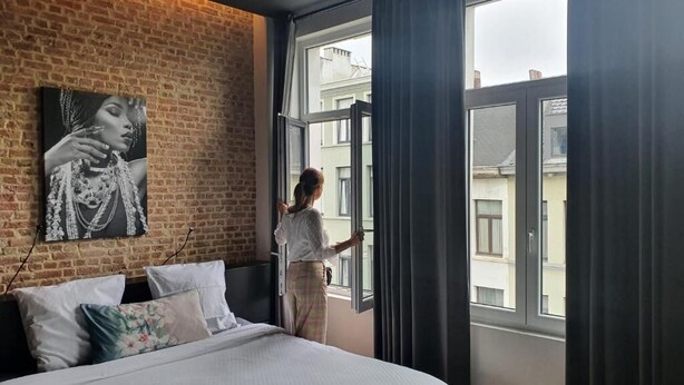Een slaapkamer met een groot bed, een bakstenen muur, een raam en een schilderij.