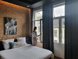 Ein Schlafzimmer mit einem großen Bett, einer Ziegelwand, einem Fenster und einem Gemälde.