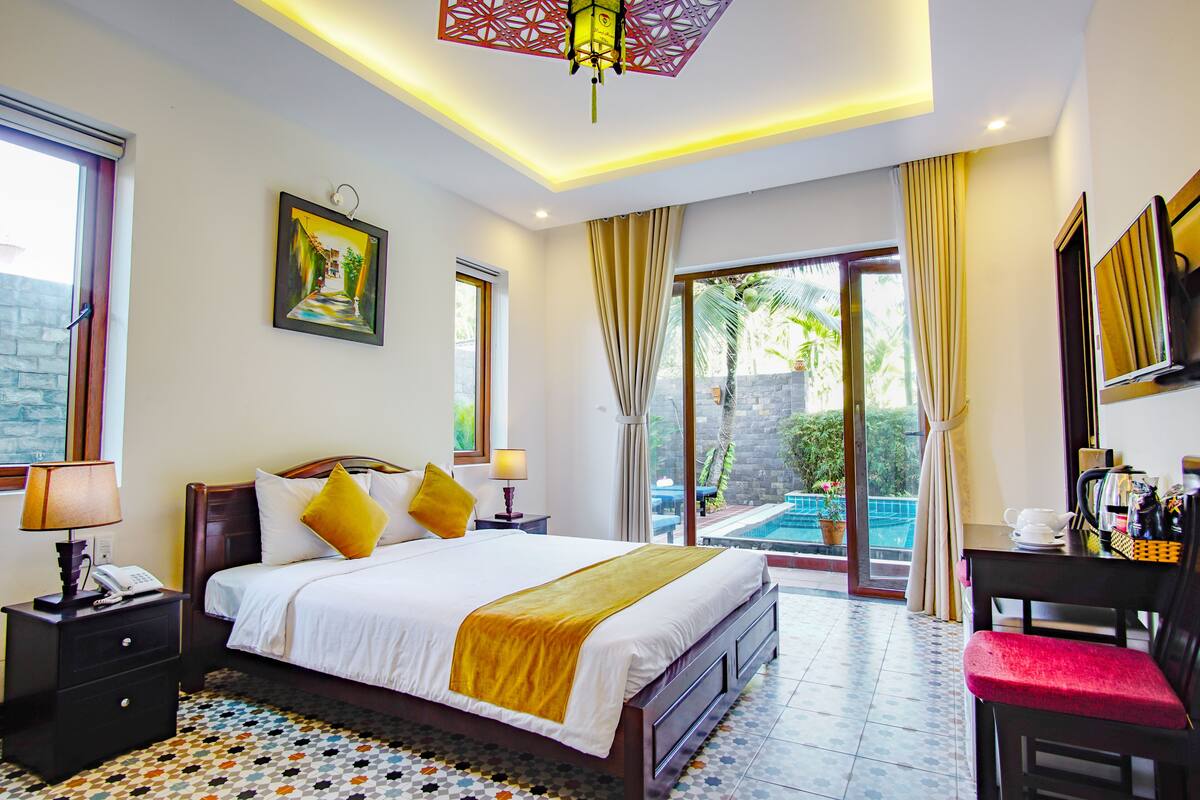 Une chambre d’hôtel avec un lit, une table de chevet, une lampe et une vue sur une piscine extérieure.