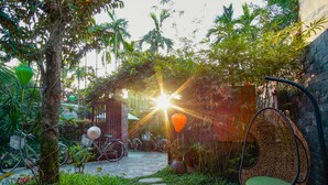 Un jardí amb una cadira d'oscil·lació de vimetla, bicicletes i un camí.