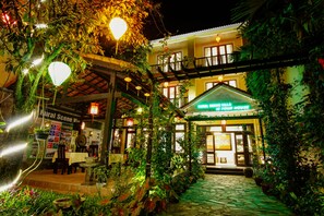 A building with a covered outdoor seating area, a sign reading 'Rural Scene Villa,' and a staircase leading to a balcony. - Rural Scene Villa (Da Nang)