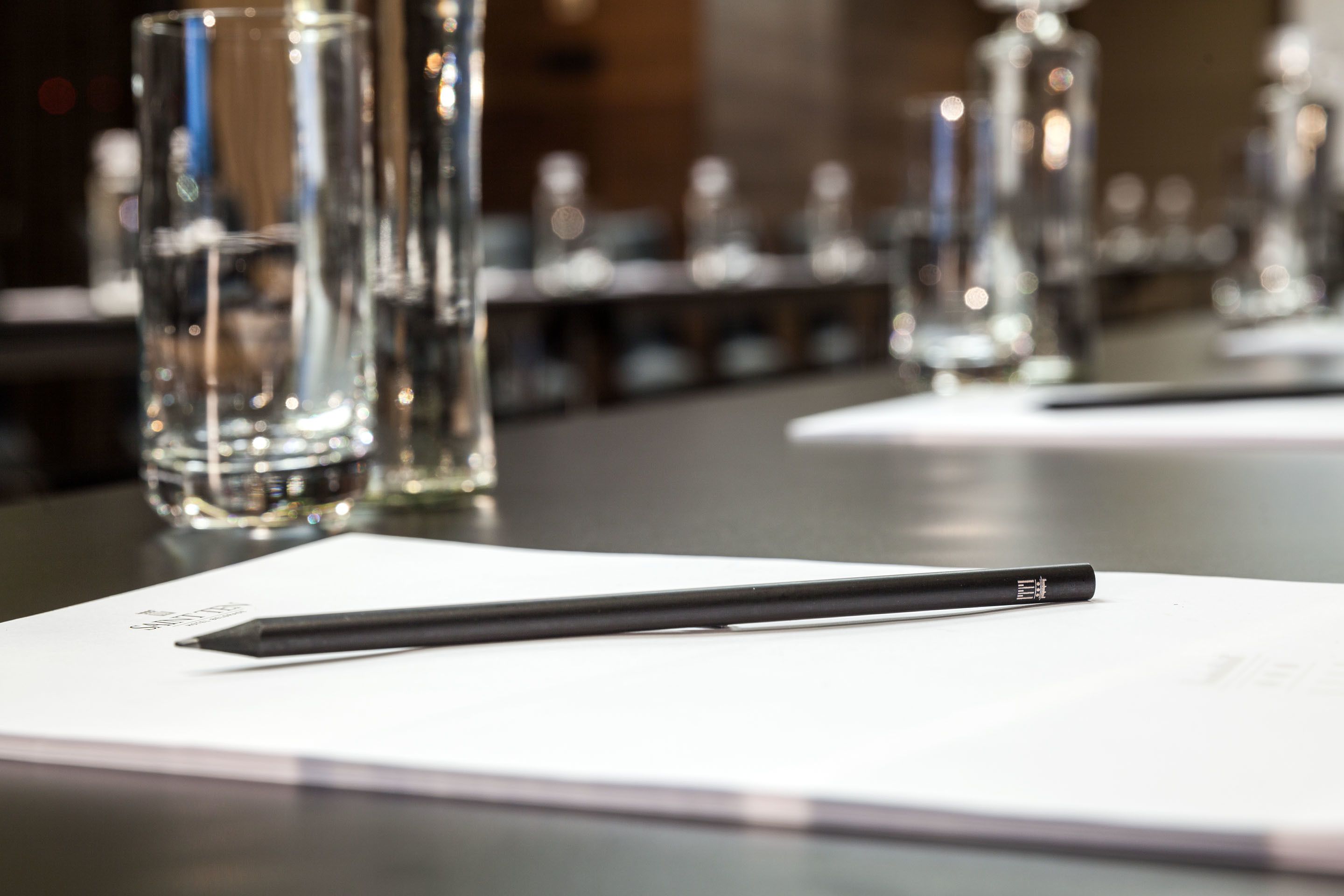 A black pen on a white piece of paper with a blurred background of tall glass bottles.
