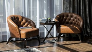 Two leather armchairs with a small round table between them, featuring a book, a cup, and a small plant.
