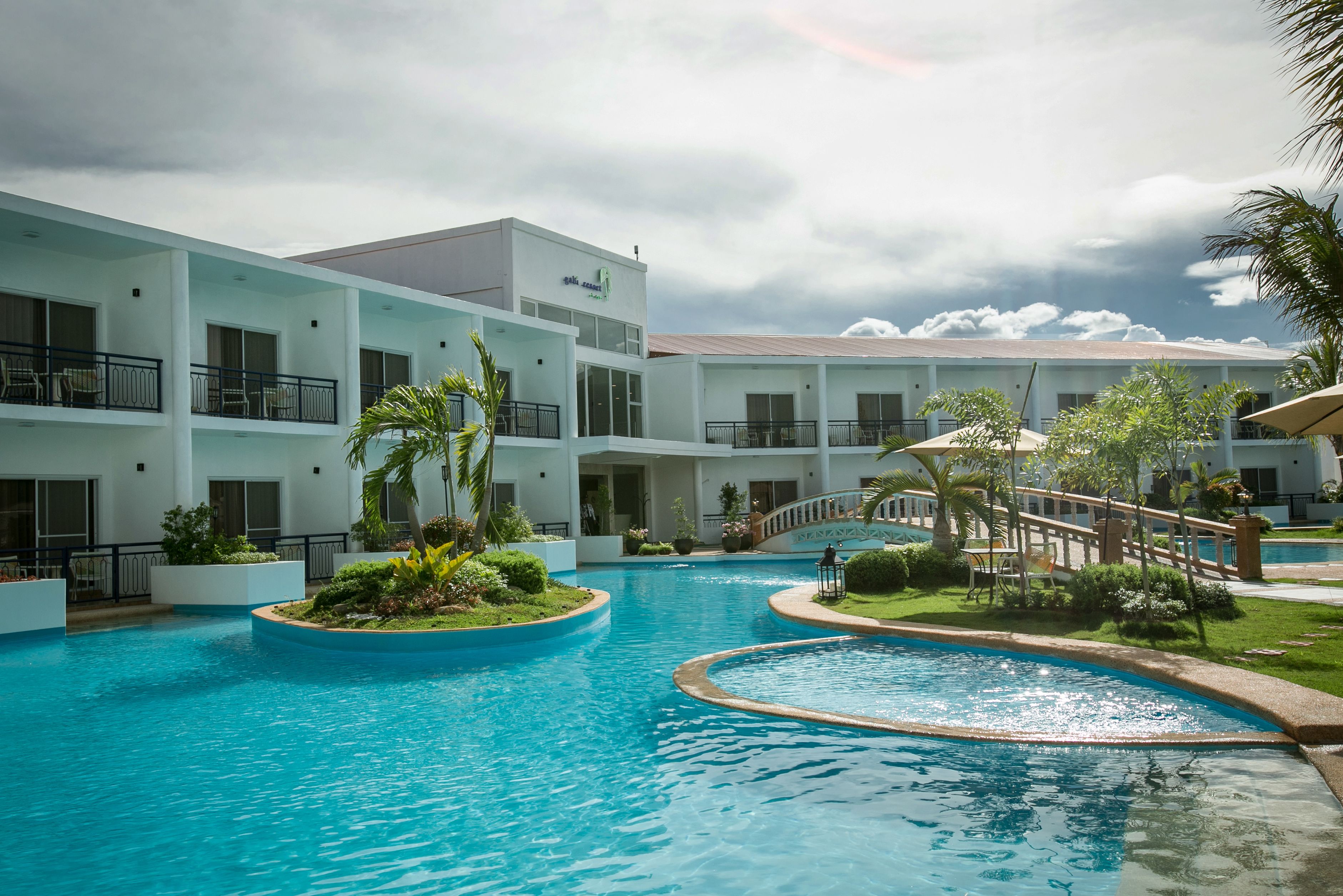 Un hotel con piscina, varios balcones y un puente cubierto.