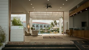 A hotel lobby with a reception desk, seating area, and a pool view. - Gabi Resort & Spa (Cordova)