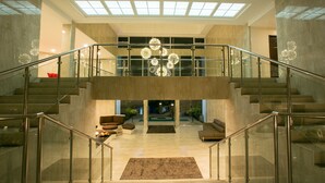 A spacious, modern lobby with a central staircase, a glass railing, and a decorative chandelier. - Gabi Resort & Spa (Cordova)