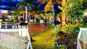 A well-lit outdoor area with a pool, lounge chairs, and palm trees. - Gabi Resort & Spa (Cordova)