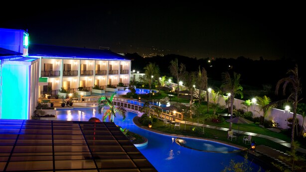 A hotel with a swimming pool, outdoor seating, and a well-lit building. - Gabi Resort & Spa (Cordova)
