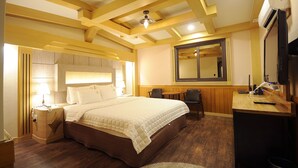 Une chambre d’hôtel avec un grand lit, une table de chevet, une lampe et un bureau avec une chaise.