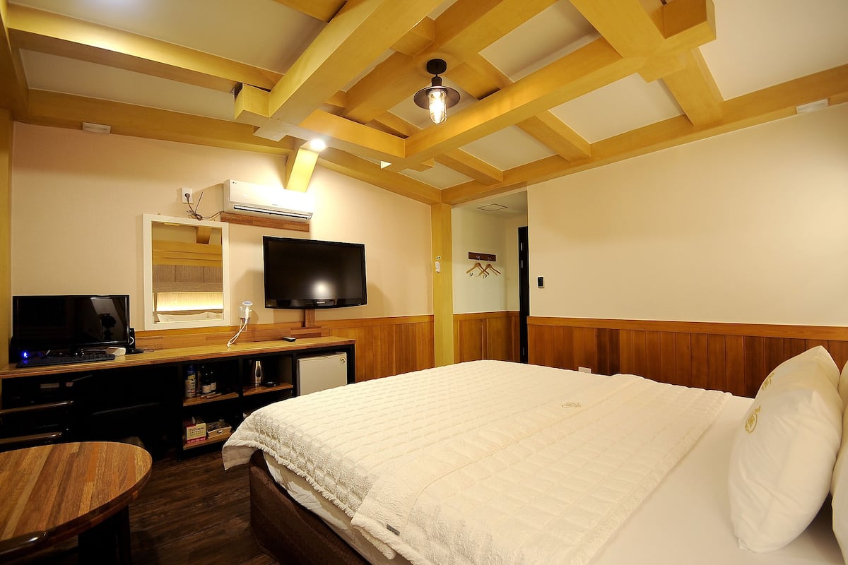 A hotel room with a bed, a TV, a desk, and a chair.
