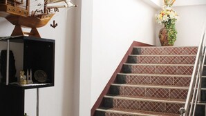 A staircase with a tiled pattern, a ship model, and a vase with flowers. - Kanmanee Inn (Chiang Rai)