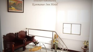A hotel lobby with a wooden bench, a glass table with flowers, a staircase, and a framed picture on the wall. - Kanmanee Inn (Chiang Rai)