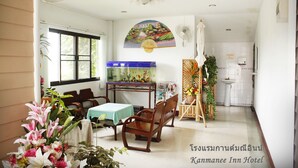 A hotel room with a dining area, a fish tank, a painting, and a bathroom. - Kanmanee Inn (Chiang Rai)