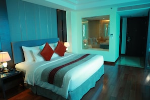 A hotel room with a large bed, a nightstand with a lamp, a mirror, and a view of a bathroom. - Summer Cua Lo Hotel (Cua Lo)
