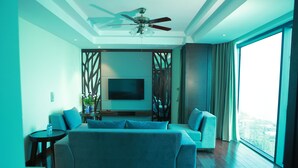 Una sala moderna con un sofá grande, una televisión y un ventilador de techo.