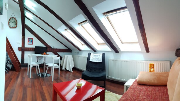A loft-style room with skylights, a dining area, a black chair, a red table, and a sofa. - Taban Hostel Zagreb - hostel (Zagreb)