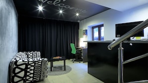 A modern living room with a black couch, a small table, a green chair, and a black reception desk. - Taban Hostel Zagreb - hostel (Zagreb)