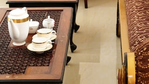 A traditional tea set on a wooden table with a patterned sofa and a dark wooden desk in the background. - Villa Ceylon (Kimbulapitiya- Katunayake)