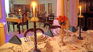 A dining table set with candles, a vase of flowers, and a floral tablecloth. - Villa Ceylon (Kimbulapitiya- Katunayake)