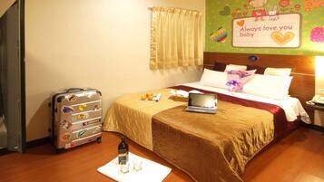A hotel room with a bed, a laptop, a suitcase, and a bottle of water on a white mat.