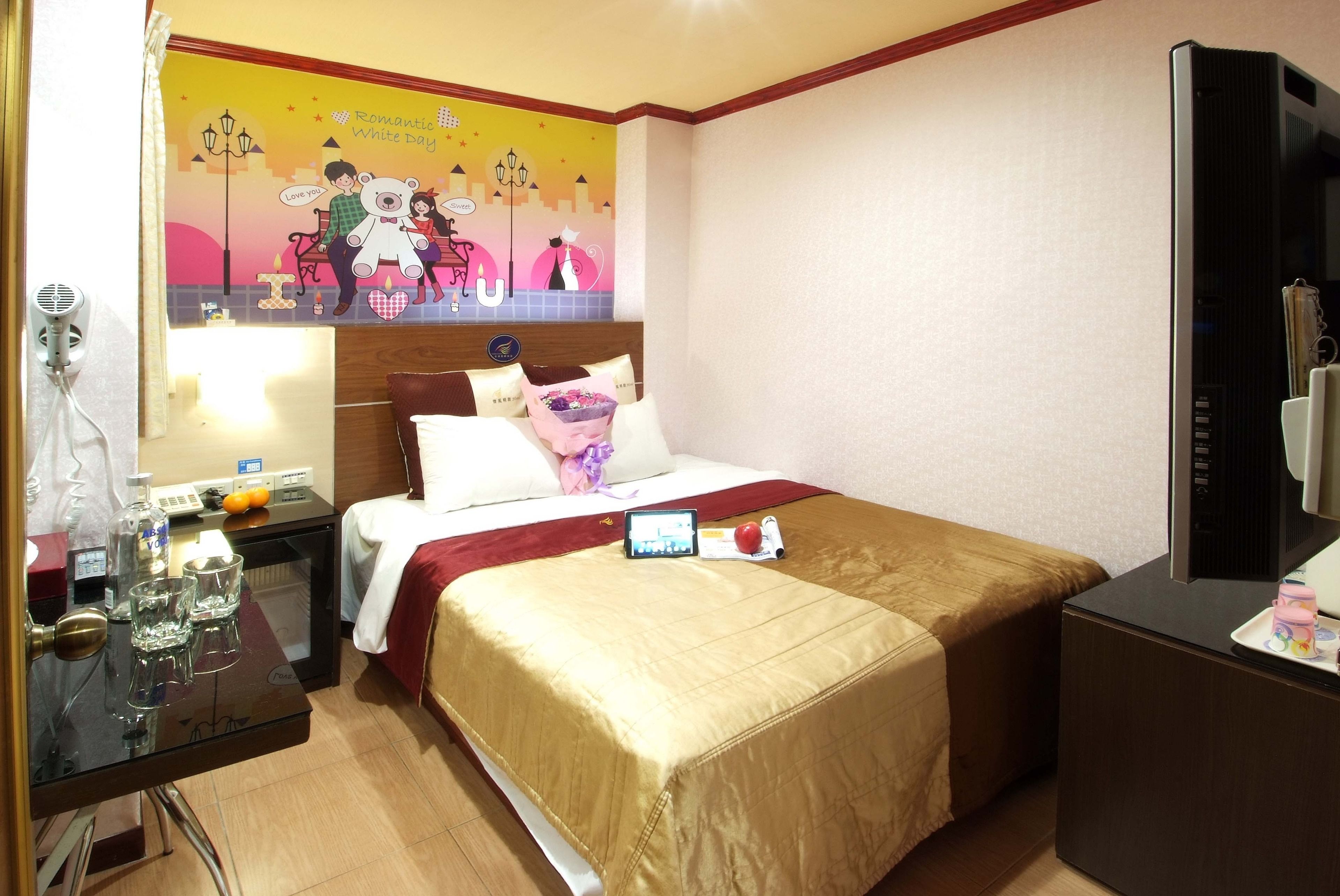 Una habitación de hotel con cama, mesita de noche y televisor.