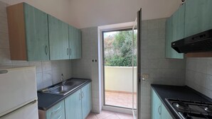 A kitchen with teal cabinets, a black countertop, a stainless steel sink, and a gas stove. - Argeste Club Vacanze (Vieste)