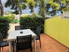 An outdoor patio with a table and chairs, surrounded by greenery and a yellow wall. - Argeste Club Vacanze (Vieste)