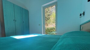 A bedroom with a bed, a wardrobe, and a window with a view of greenery. - Argeste Club Vacanze (Vieste)