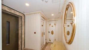 Un couloir doté d’un sol en marbre, d’un banc en bois et d’un grand miroir décoratif accroché au mur.