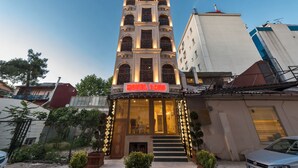 Un hôtel à l’architecture classique, caractérisé par une entrée imposante avec des marches et une enseigne.