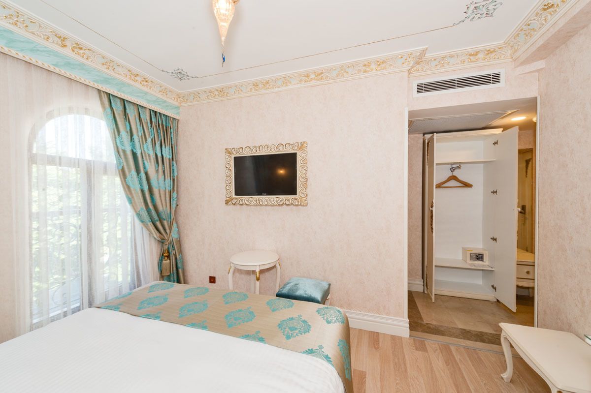Una habitación de hotel con cama, televisión, una mesita y un armario.