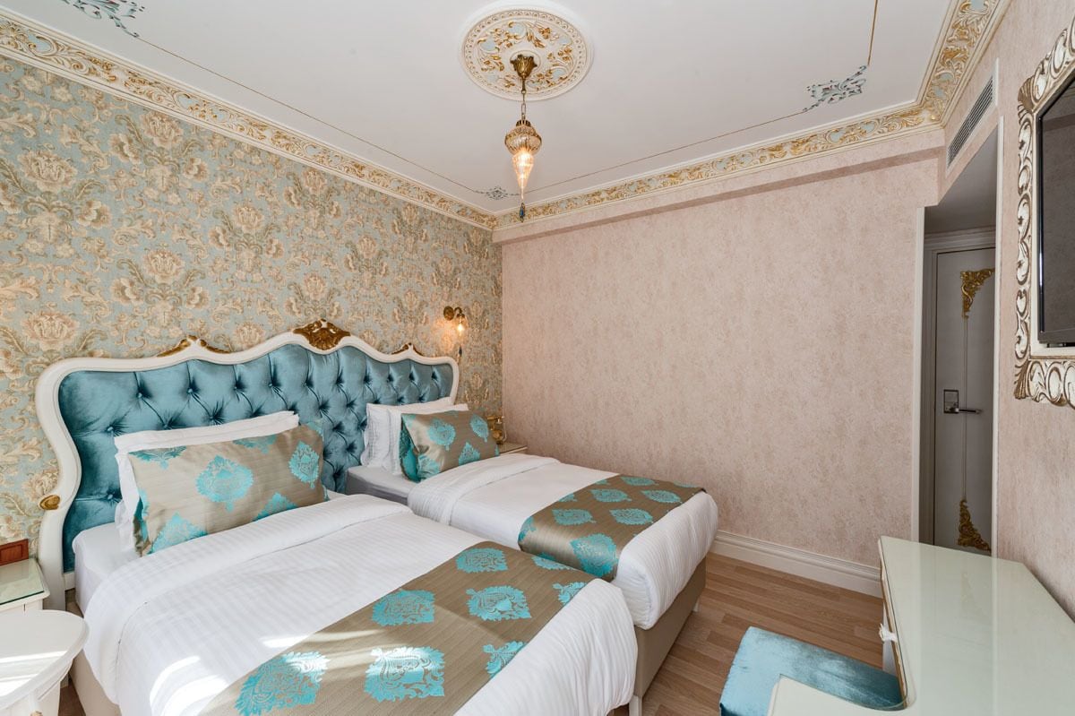 Un dormitorio con dos camas, papel tapiz decorativo y un candelabro.
