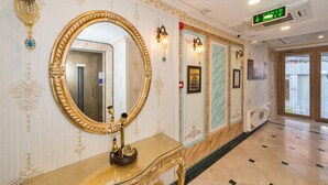 Un couloir agrémenté de décorations murales élaborées, d’un grand miroir et d’un panneau de signalisation numérique indiquant la sortie.